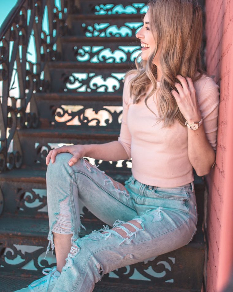 Smiling woman sitting on a pink-lit stairway